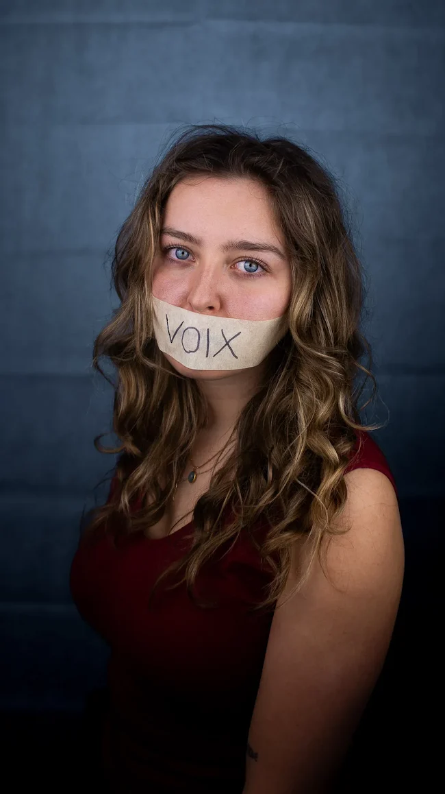 Frau mit Klebeband über dem Mund mit „VOIX“, Blick leicht zur Seite